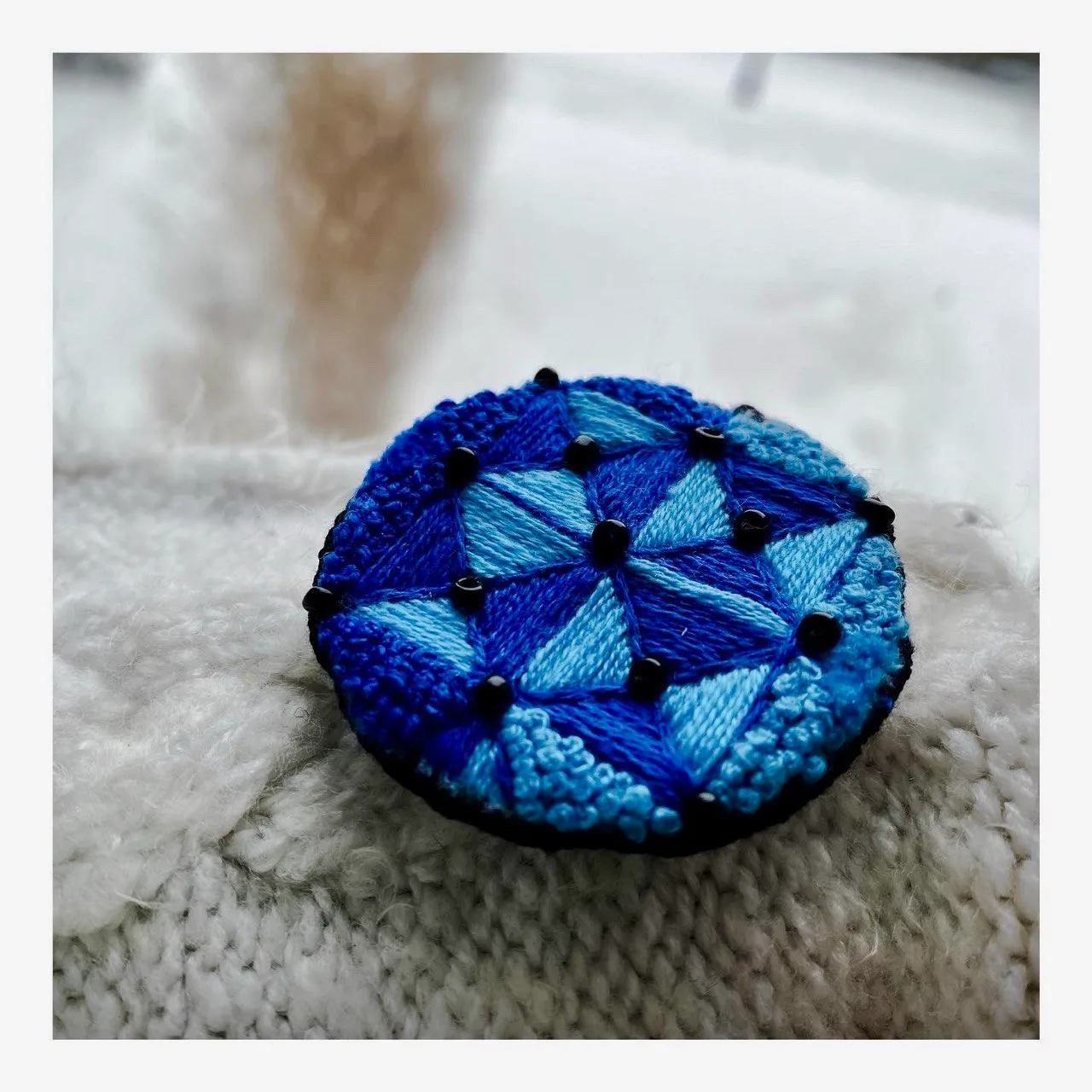 Round embroidered brooch in blues with black beads