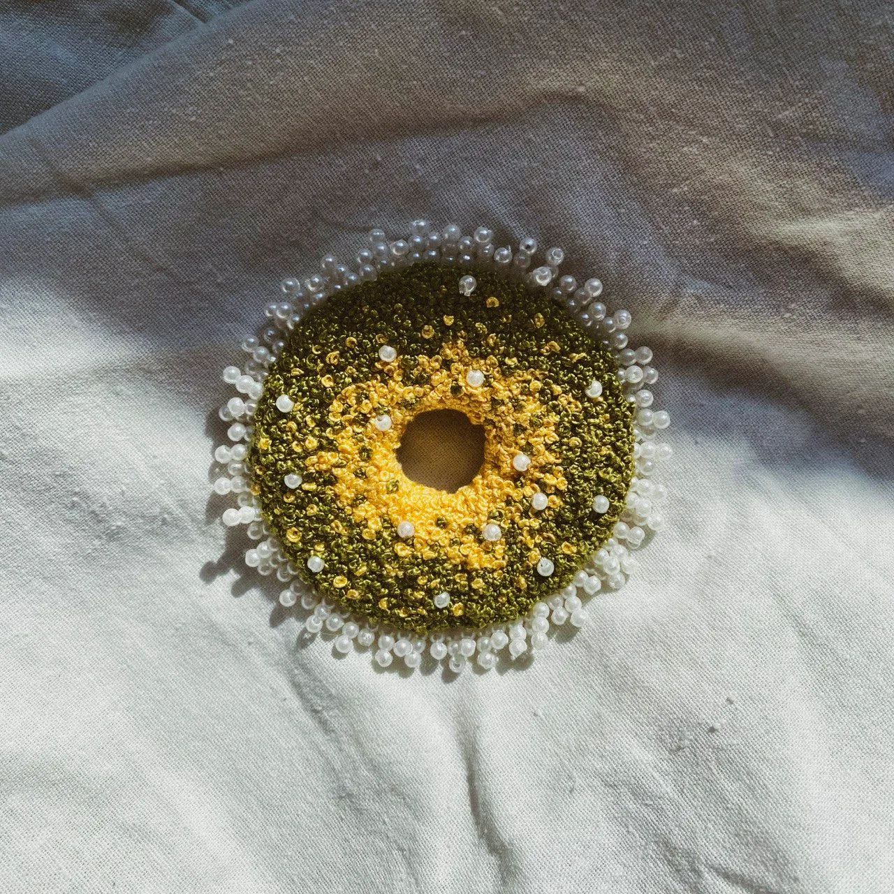 Embroidered circle in yellow and olive green, edged with white beads
